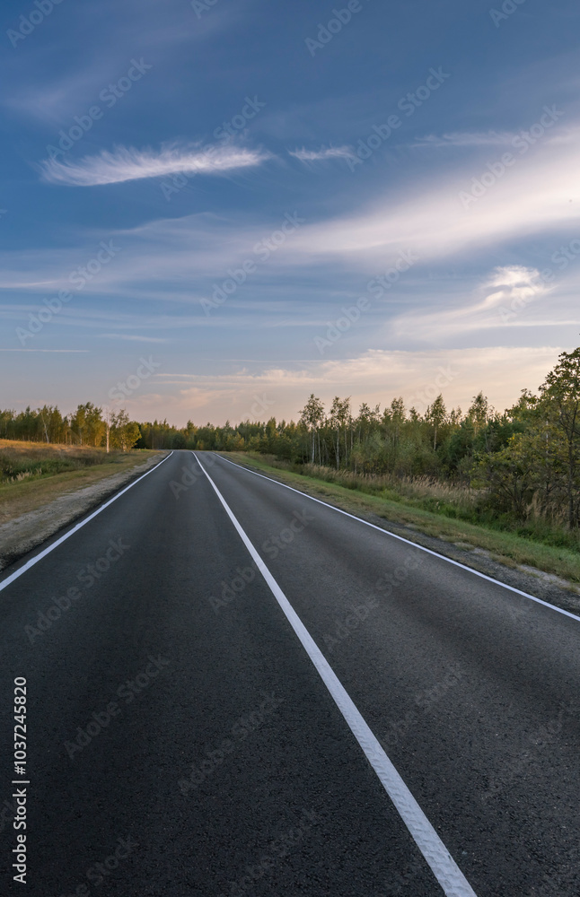 A long, empty road with a blue sky in the background A long, empty road with a blue sky in the background