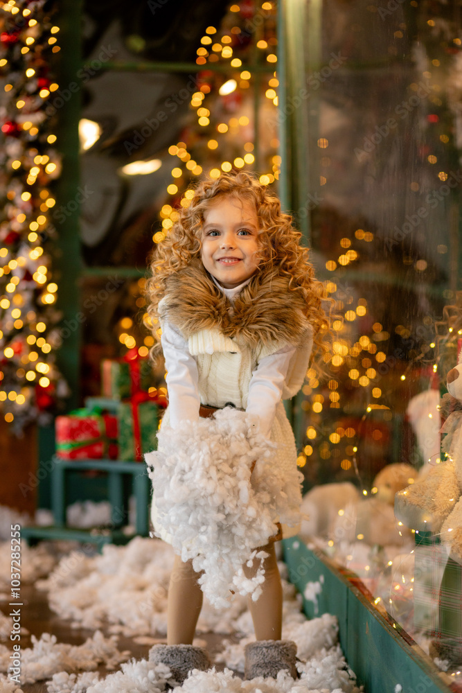 A little curly girl throws artificial snow in the interior of the Christmas studio. dreams and joys Christmas Eve. Christmas. The holiday is coming A little curly girl throws artificial snow in the interior of the Christmas studio. dreams and joys Christmas Eve. Christmas. The holiday is coming