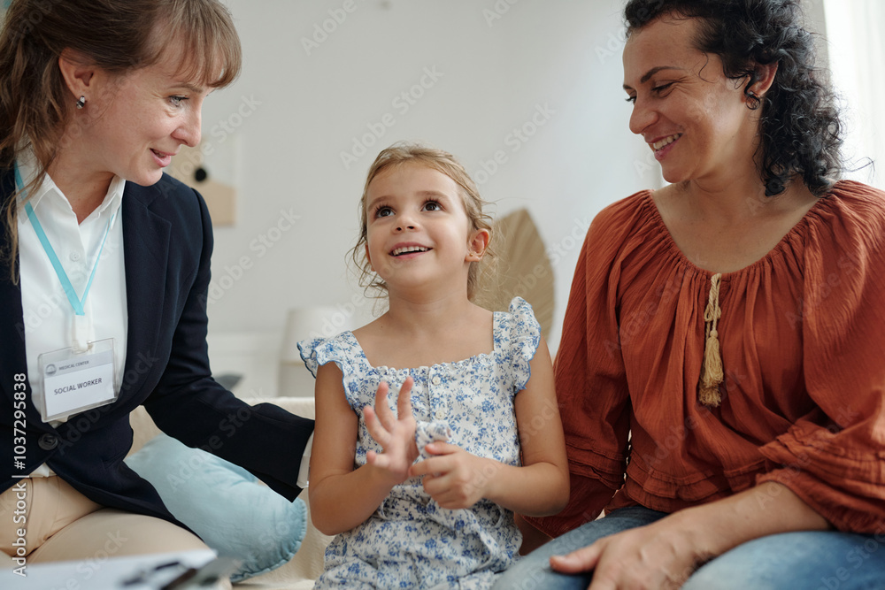 Little girl talking to social worker while sitting on sofa with her ...