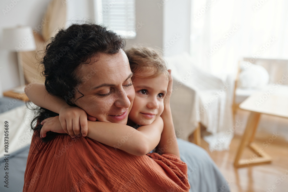 Little girl embracing her mother while they resting in the room Little girl embracing her mother while they resting in the room