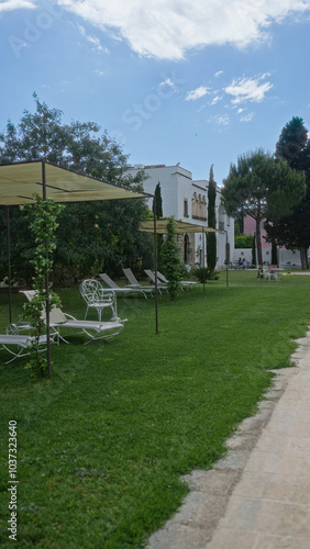 Wallpaper Mural Lounge chairs under canopies adorn a lush green lawn outside a traditional white puglian villa in italy, showcasing serene outdoor relaxation and mediterranean architecture. Torontodigital.ca