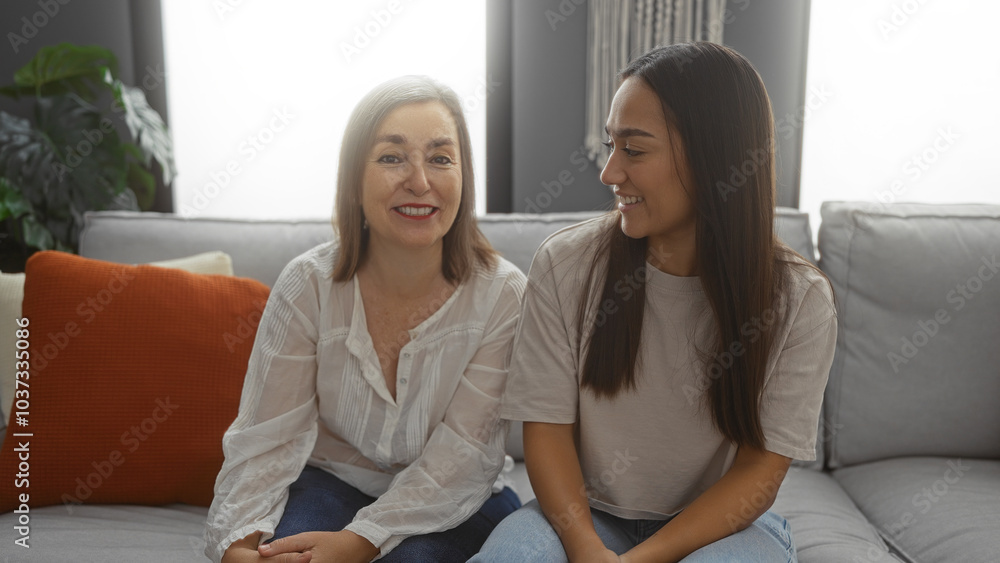 Mother and daughter smiling together in a cozy living room, emphasizing family love and connection between two women in an indoor home setting. Mother and daughter smiling together in a cozy living room, emphasizing family love and connection between two women in an indoor home setting.