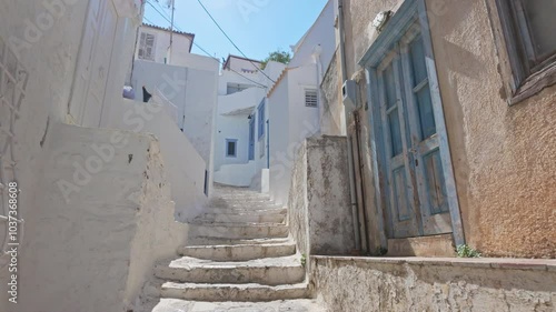 A smooth gimbal steadicam shot captures a slow ascent up the stone steps of Hydra’s picturesque, cobbled streets. The midday summer sun casts bright light on the traditional alleyways.