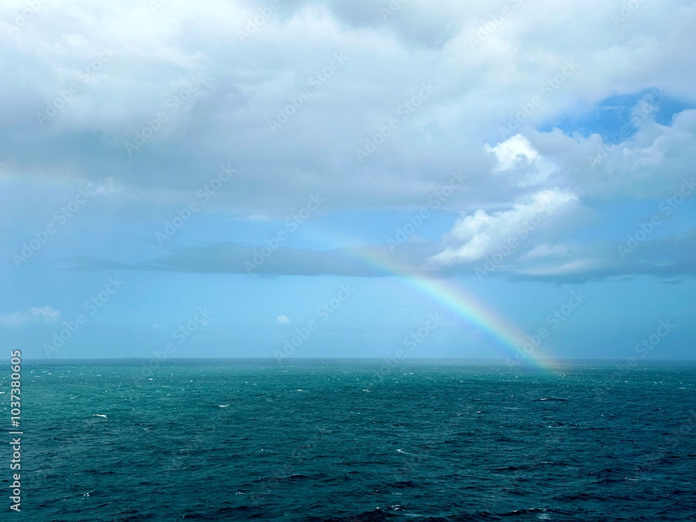 A clear rainbow in the middle of the ocean breaking through the clouds into the sea A clear rainbow in the middle of the ocean breaking through the clouds into the sea