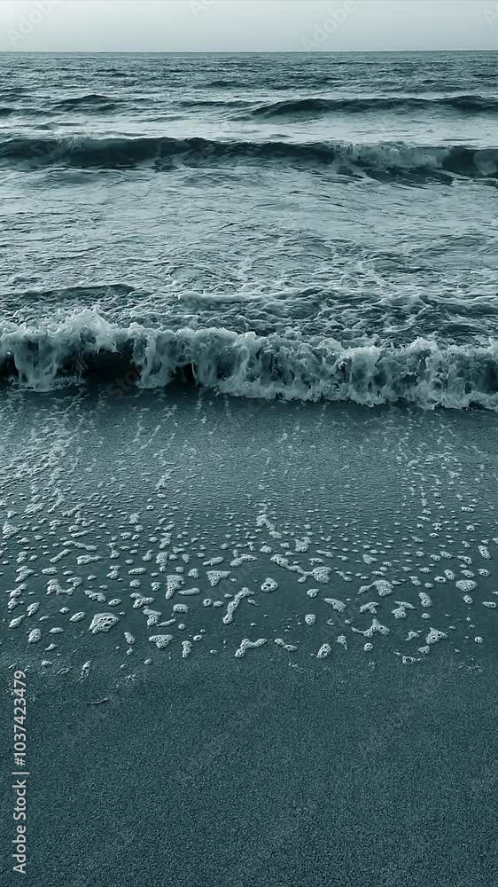 Sea waves rolling on a sandy beach on the seashore in summer during sunset sunrise. Nature. Natural background. Vertical Sea waves rolling on a sandy beach on the seashore in summer during sunset sunrise. Nature. Natural background. Vertical