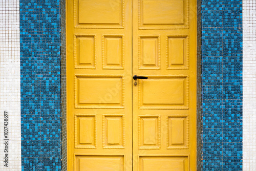 Puerta amarilla en fachada de baldosa photo