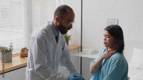 Plastic surgeon showing young female patient images of before-and-after surgery results and then drawing lines on her face with marker pen during preparation for procedure in clinic