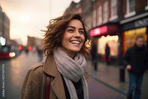 Beautiful young woman walking in the city at sunset, looking at camera