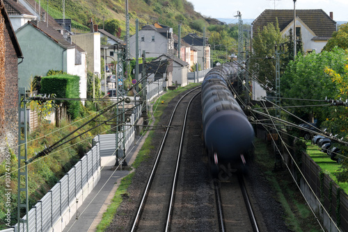 Bahnstrecke durch Ort mit Lärmschutzwänden zur Reduzierung von Bahnlärm und durchfahrender Güterzug mit Kesselwagen - Stockfoto photo