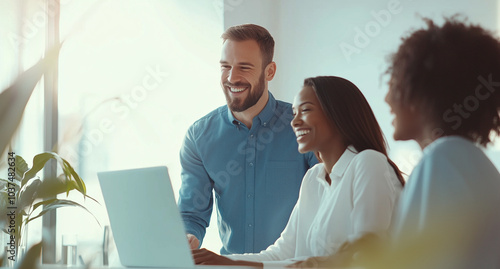 Three diverse business people laughing and working together on a laptop in a modern office, side view. A man with short hair wearing a blue shirt is standing behind a woman sitting at a table,