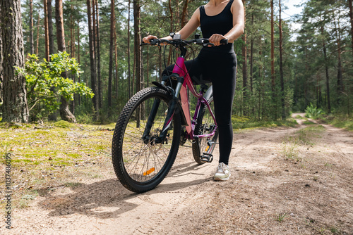 Bicycle parked on a forest trail, suggesting a perfect setting for mountain biking. The trail winds through dense trees, providing a scenic and adventurous backdrop.