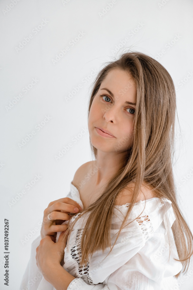 Pretty 30s woman looking at camera in white top shirt exposing shoulder. Studio portrait. Boho style dress. Natural beauty face. Concept of tenderness and femininity. Flirting look Pretty 30s woman looking at camera in white top shirt exposing shoulder. Studio portrait. Boho style dress. Natural beauty face. Concept of tenderness and femininity. Flirting look