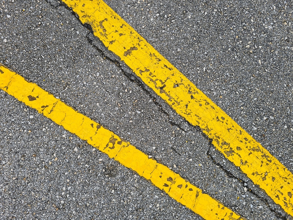 Fototapeta premium two thick old yellow painted lines on gray asphalt