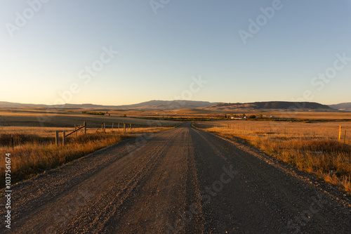 Rural country dirt gravel road, western ranch lane at sunrise, rural street at sunset, centered horizon