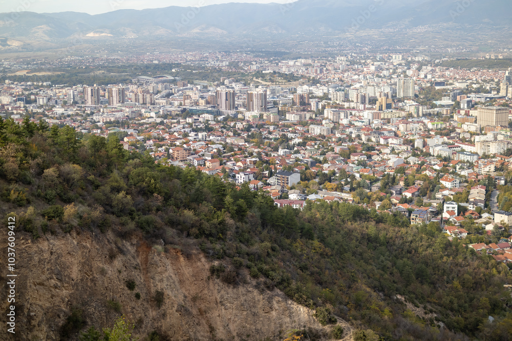 Obraz premium Skopje, a thriving urban panorama The city of Skopje, seen from above Aerial view of the Macedonian capital Skopje, a mosaic of colors and shapes where the mountains meet the metropolis.
