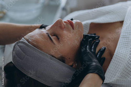Cosmetologist performs a facial peeling procedure on a young woman.