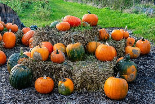 A festive fall display. There are three bales of hay, a flag that reads 