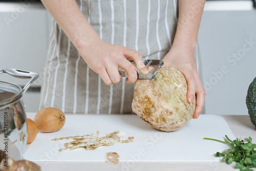 Woman peeling a celery root or celeriac in the kitchen photo