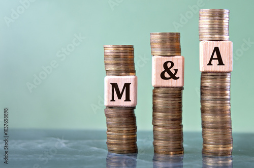 Foto M and A - acronym on wooden cubes on stacks of coins