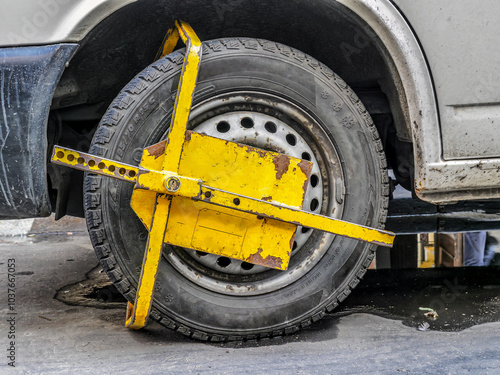 фотографія Yellow Wheel Clamp on a Parked Vehicle Tire