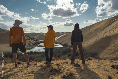 A group of friends stands on a slope against the background of the sky, sand and river. Friends are standing on the observation deck. Tourists in the desert on a beautiful background.