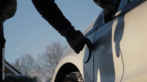 Charging EV or PHEV in winter. Gloved hand inserts a power connector into electric vehicle. Unrecognizable person connects charging cable to an electric car and charges the batteries photo