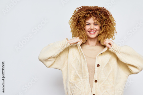 smiling woman in cozy sweater, cheerful expression on a light blue background, showcasing a trendy winter look, perfect for fashion and lifestyle themes