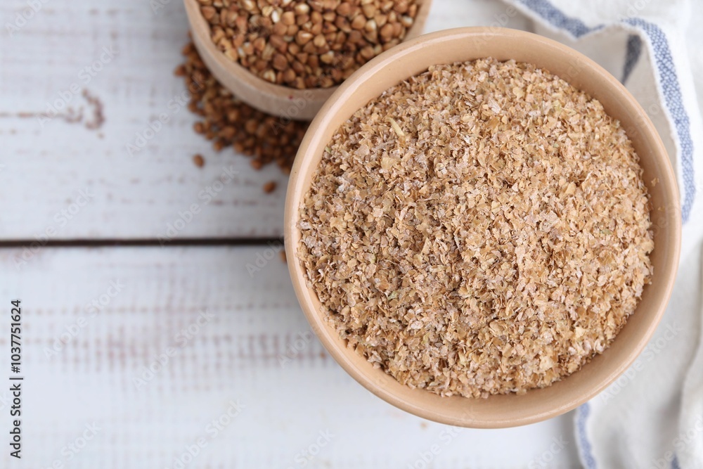 Buckwheat bran in bowl and grains on white wooden table, top view. Space for text Buckwheat bran in bowl and grains on white wooden table, top view. Space for text