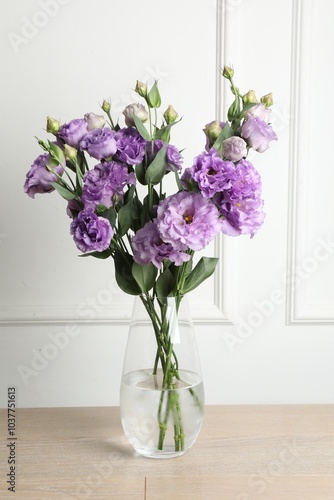 Vase with beautiful eustoma flowers on wooden table