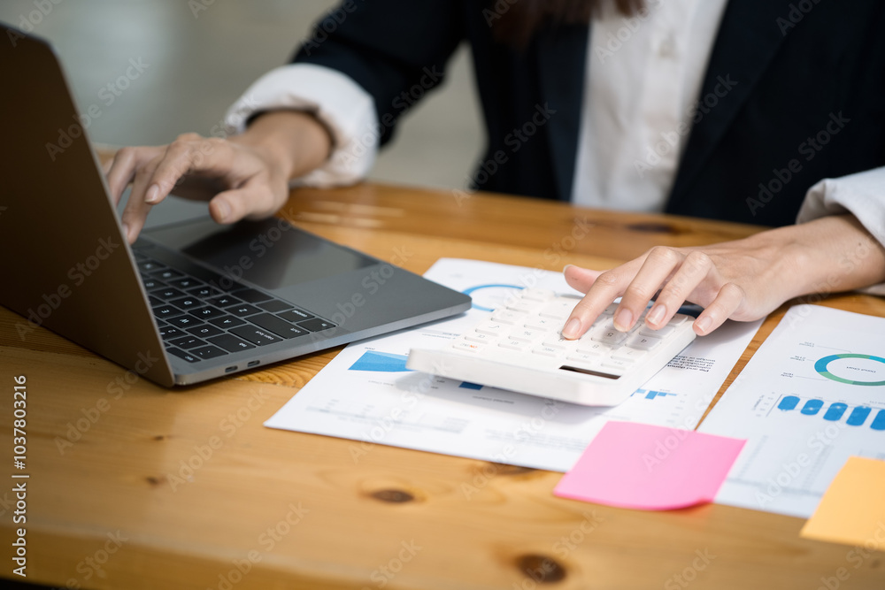 Close up of hands typing on laptop keyboard and working on document paperwork and calculator for cost financial marketing Close up of hands typing on laptop keyboard and working on document paperwork and calculator for cost financial marketing