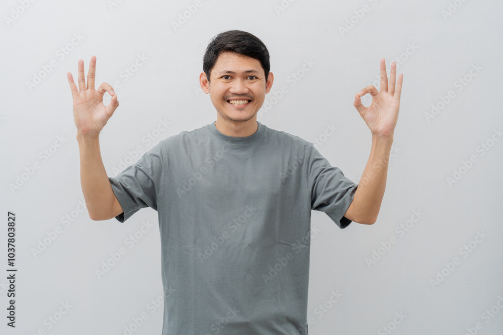 Happy expression of adult Asian man doing OK sign with casual t-shirt isolated on white background Happy expression of adult Asian man doing OK sign with casual t-shirt isolated on white background
