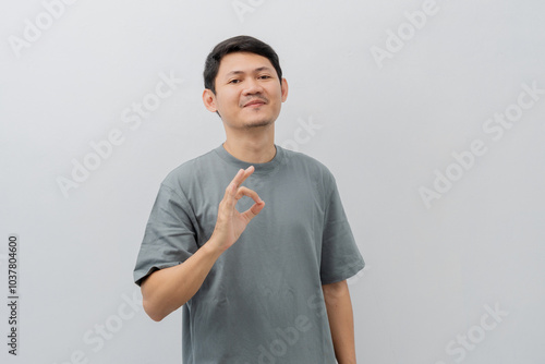 Happy expression of adult Asian man doing OK sign with casual t-shirt isolated on white background photo