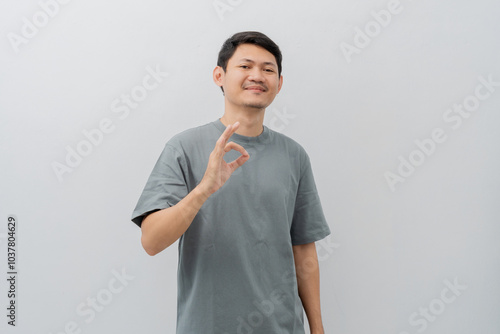 Happy expression of adult Asian man doing OK sign with casual t-shirt isolated on white background photo