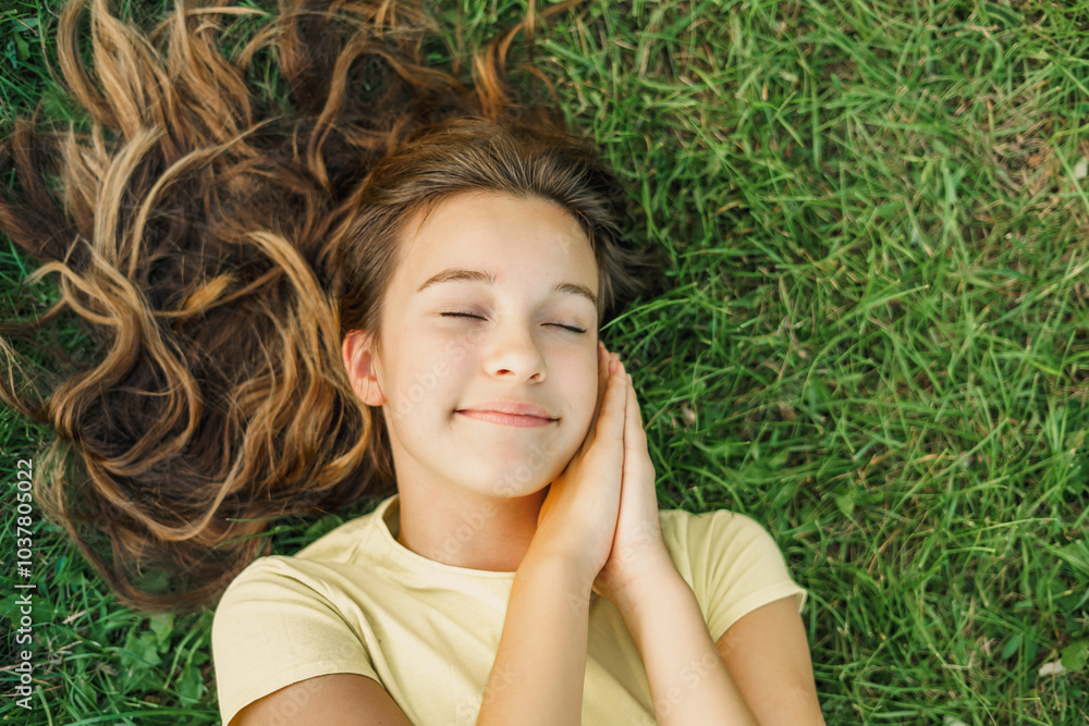 Close up top view high angle photo beautiful young girl child dreamily closed eyes her hands on cheeks natural background green grass Close up top view high angle photo beautiful young girl child dreamily closed eyes her hands on cheeks natural background green grass