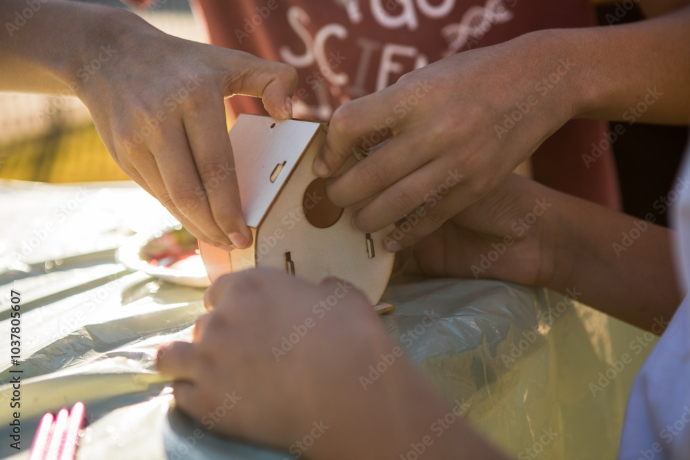 Obraz premium Kids hands making wooden toy house. hobby or leisure. DIY wooden house project.