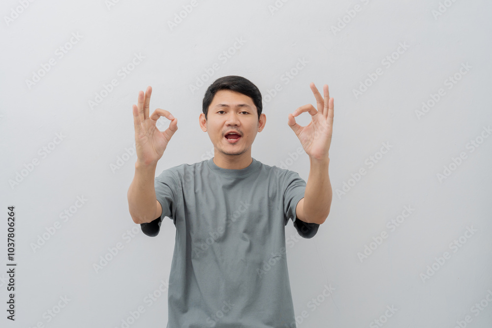 Happy expression of adult Asian man doing OK sign with casual t-shirt isolated on white background Happy expression of adult Asian man doing OK sign with casual t-shirt isolated on white background