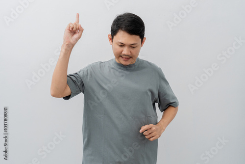 Sad and disappointed expression of adult Asian man pointing fingers with casual t-shirt isolated on white background photo