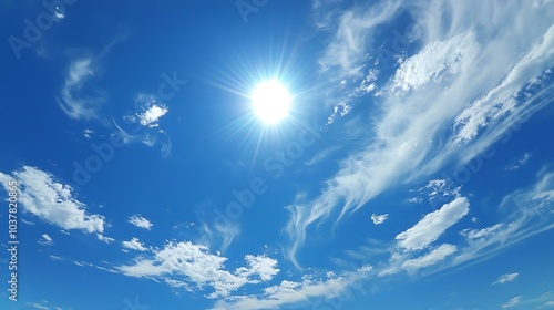 Fototapeta Naklejka Na Ścianę i Meble -  A clear, bright blue sky with the sun shining and only a few wispy clouds scattered around