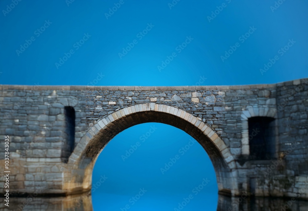 A stone arch bridge with a blue sky background. A stone arch bridge with a blue sky background.