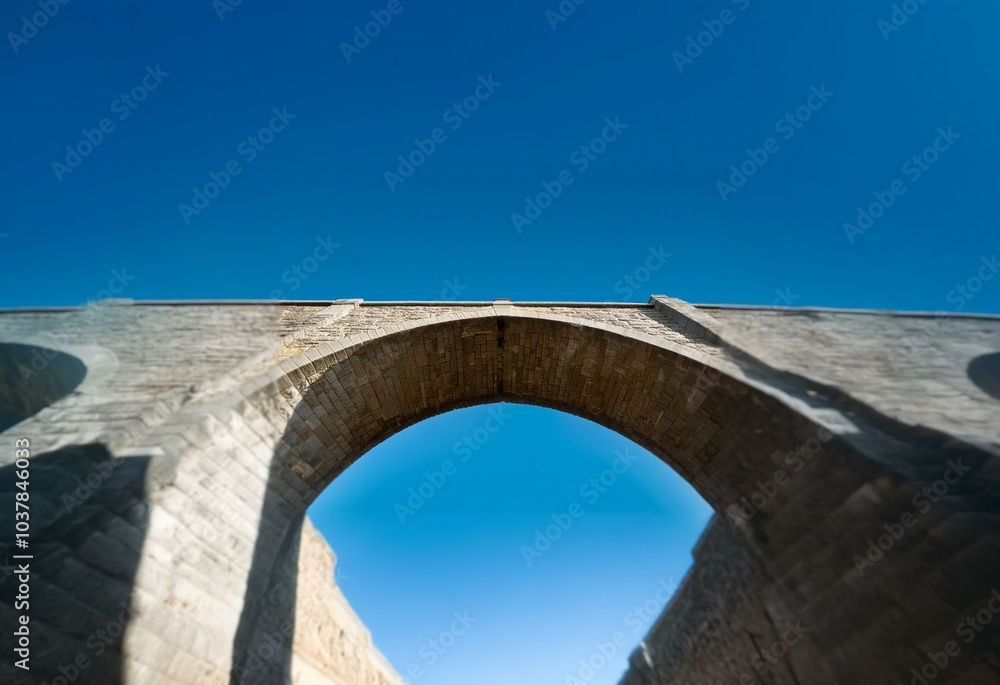 A stone archway frames a clear blue sky. A stone archway frames a clear blue sky.