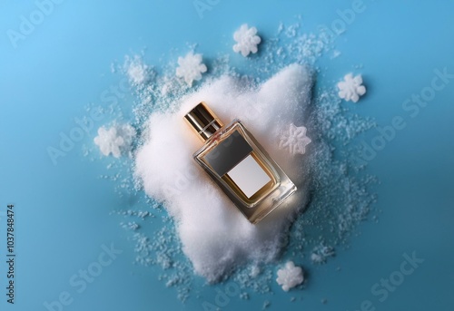 A perfume bottle sits atop a pile of faux snow surrounded by snowflakes on a blue background. photo