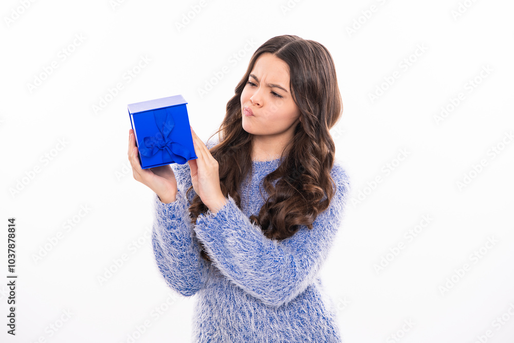 Christmas and New Year concept. Smiling teen kid girl in pink dress holding a big present gifts box on background with copy space. Teenager girl celebrating birthday, holding gift. Christmas and New Year concept. Smiling teen kid girl in pink dress holding a big present gifts box on background with copy space. Teenager girl celebrating birthday, holding gift.