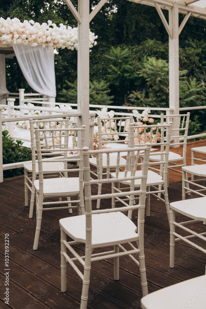 Obraz premium A neat row of pristine white chairs is perfectly lined up along a beautifully crafted wooden deck, creating an inviting atmosphere