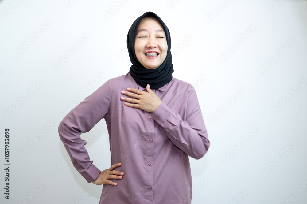 Portrait of emotional Indonesian woman laughing and wearing a purple shirt and black headscarf is laughing while pointing with her hands. isolated on white background Portrait of emotional Indonesian woman laughing and wearing a purple shirt and black headscarf is laughing while pointing with her hands. isolated on white background