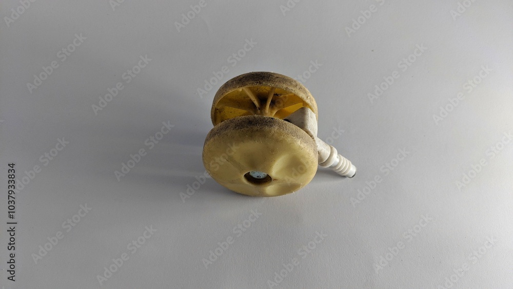 A small, yellow caster wheel with a central stem and a spark plug-like attachment at the end. The wheel has a ridged surface and appears to be made of a plastic or rubber material. A small, yellow caster wheel with a central stem and a spark plug-like attachment at the end. The wheel has a ridged surface and appears to be made of a plastic or rubber material.