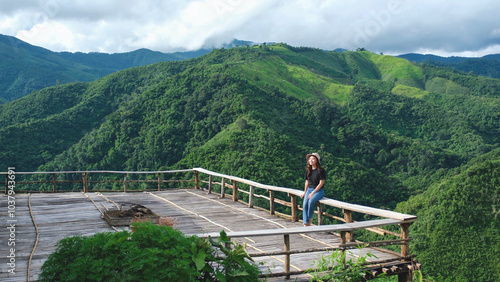 A woman sitting on wooden terrace with greenery mountain views