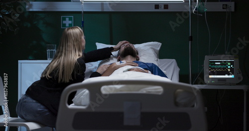 Exhausted tired young woman enters the hospital ward of his husband sits and supports while man in coma .