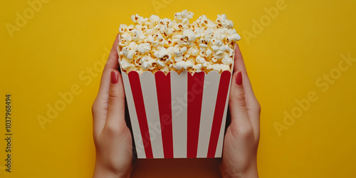 two hands full holding a popcorn box, isolated on yellow background