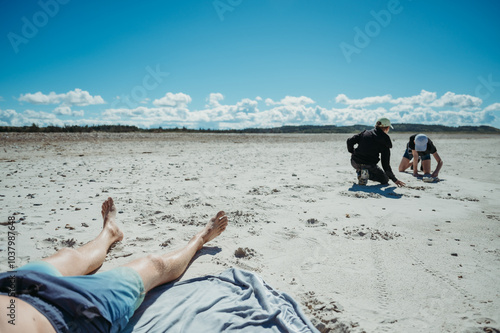 fathers watches sons play on Slettestrand Beach, Fjerritslev, Denmark. photo