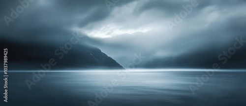  A large body of water lies before a distant mountain, its peak obscured by a cloud-filled sky A foreground presents another body of water